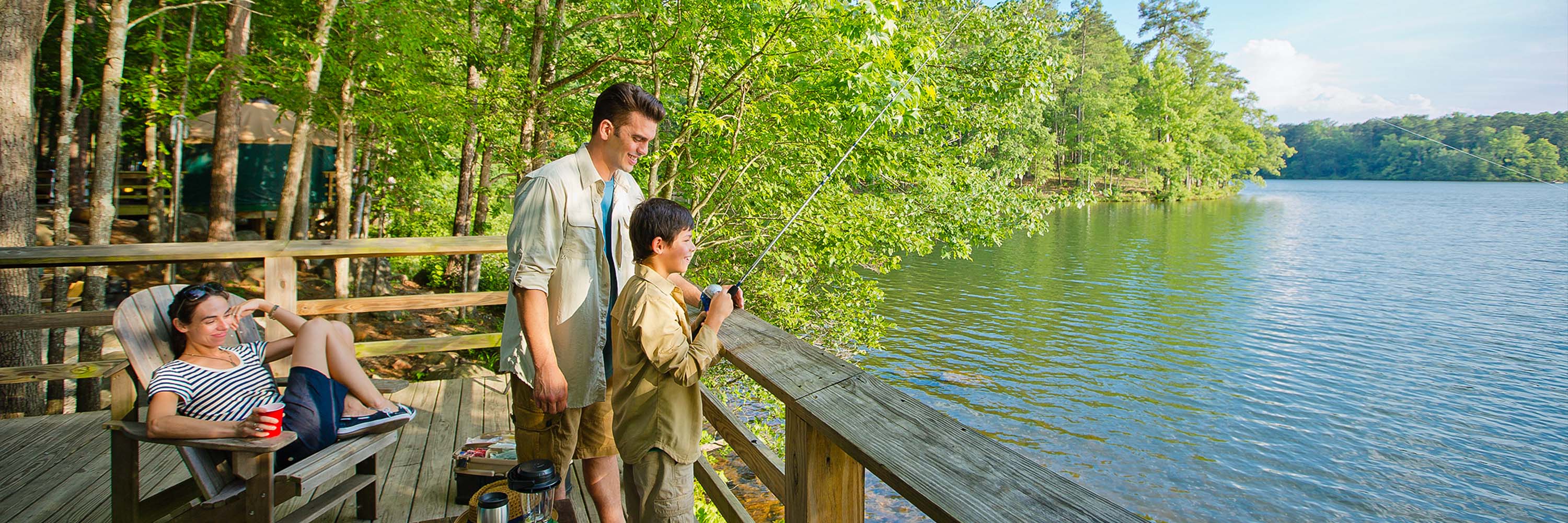 Family enjoys fishing off the deck of a cabin at Fort Yargo on a summer day