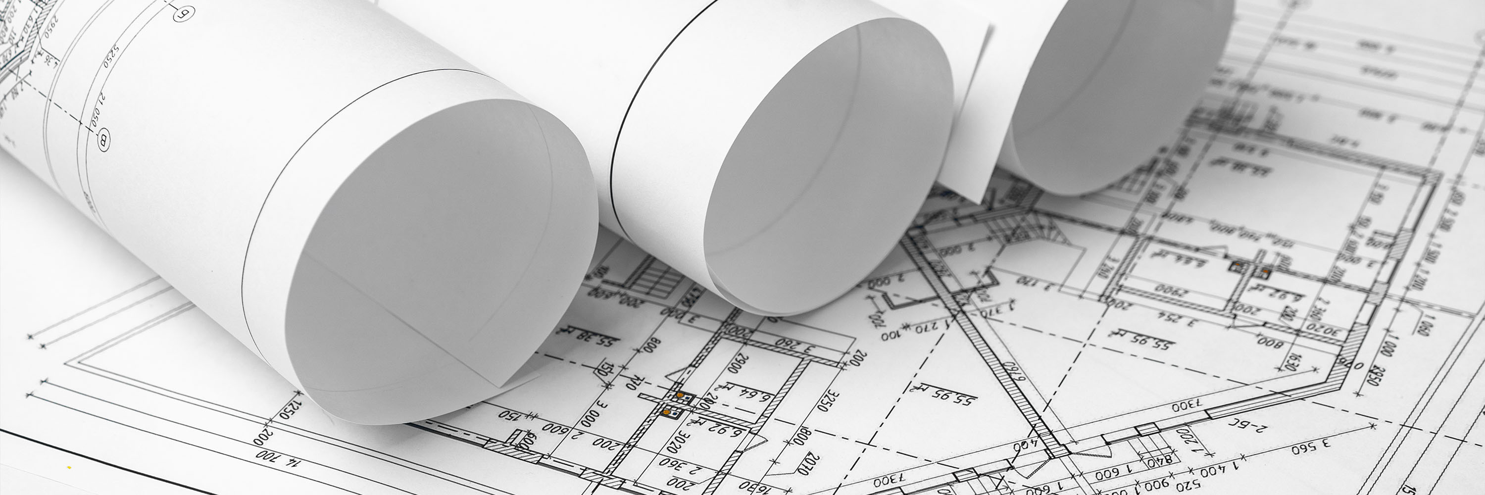 Three rolls of blueprints sitting on an architectural table